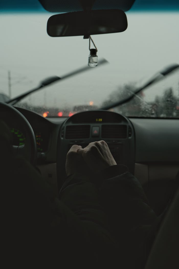 How to Prepare Your Wiper Blades for Winter Two people bump fists inside a car during a rainy day, showcasing friendship and connection.